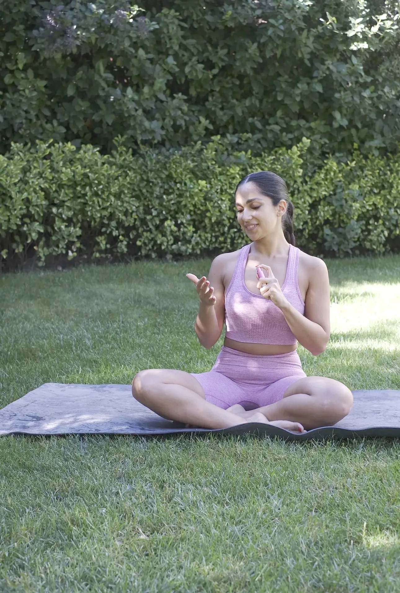 Sepideh seated on a mat in the garden, guiding breathing